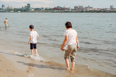 Mother and child walking on a sandy beach. cool water in the sea. walk along the beach barefoot.