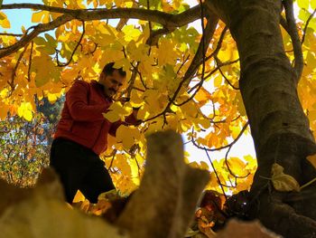 Low angle view of man standing by tree during autumn