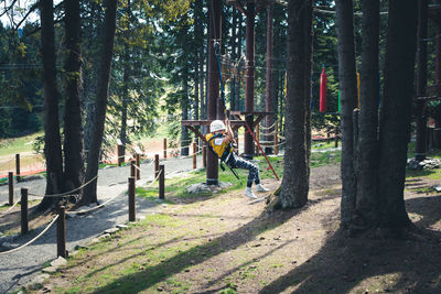 Carefree boy zip lining and having fun after roper course in the forest.