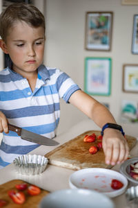 Boy cutting strawberry at kitchen