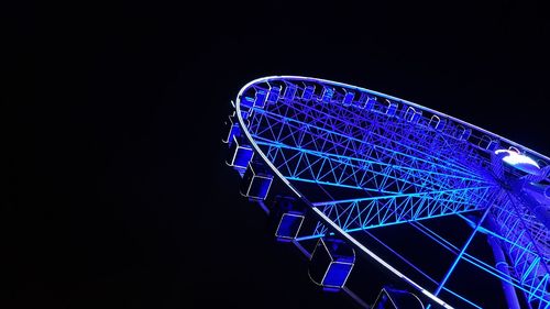 Low angle view of illuminated ferris wheel against blue sky