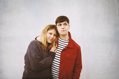 Portrait of young couple standing against wall