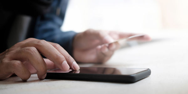 Close-up of hand holding smart phone on table