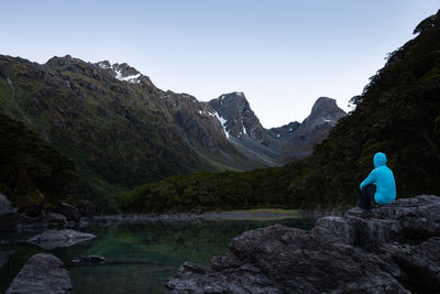 Rear view of man looking at mountains against clear sky