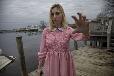 Portrait of woman standing on pier against sky