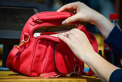 Cropped hands of woman holding red bag at home