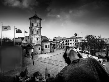 Rear view of woman standing by temple against sky in city