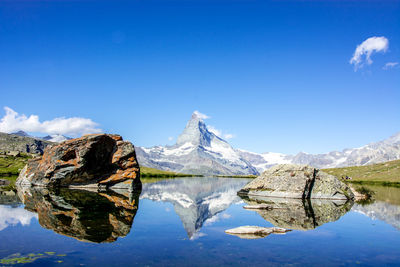 Scenic view of lake and mountains against blue sky