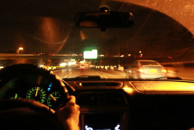 Midsection of person seen through car windshield at night