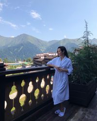 Full length of woman standing at balcony with mountains in background