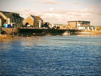 Houses by sea against sky in city