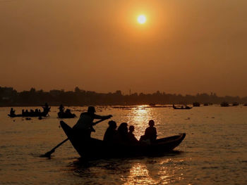 Silhouette people on boat in sea against sky during sunset