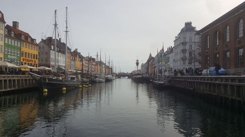 Canal amidst buildings in city against sky