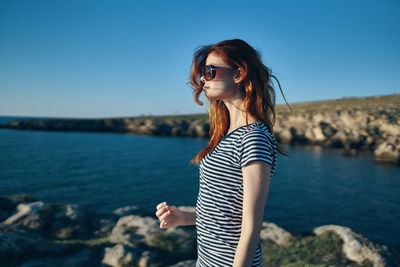 Young woman standing against blue sky