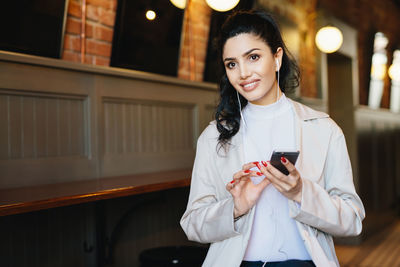 Portrait of smiling young woman using mobile phone