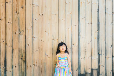 Girl standing against wooden wall