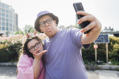 Playful brother and sister making faces and taking selfie through smart phone