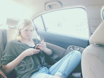 Portrait of woman using mobile phone in car