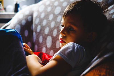 Close-up of cute boy sitting on sofa at home