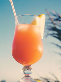 Close-up of orange juice in glass against sky