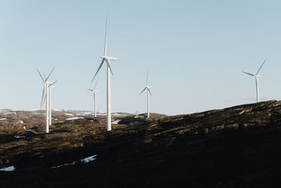 Windmills on field against clear sky