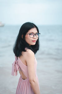 Portrait of young woman standing by sea