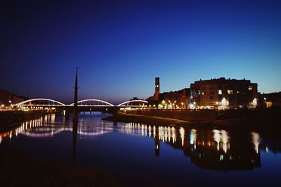 Illuminated bridge over river against blue sky at night