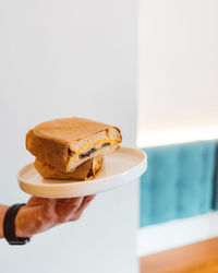 Unknown man hand holding fresh fried sandwich on white plate in restaurant. breakfast concept