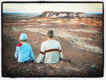 Rear view of couple sitting on rock