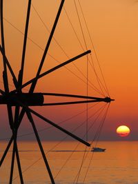 Silhouette sailboat on sea against orange sky