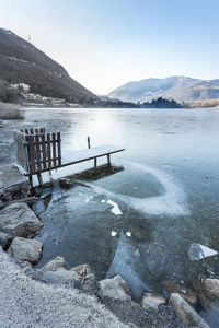 Scenic view of lake by snowcapped mountains against sky