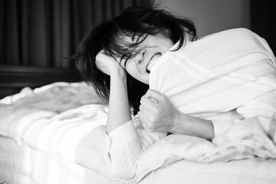 Portrait of woman lying on bed at home