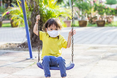 Full length of girl sitting on slide at playground