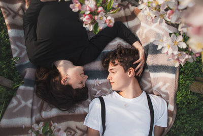 Strong love between two young people lying on a blanket under apple trees. candid portrait of couple