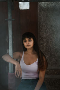 Portrait of young woman standing against wall