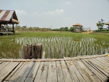 Built structure on field by houses against sky