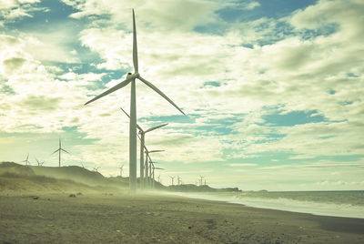 Wind turbines on land against sky