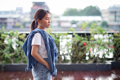 Young woman standing against railing