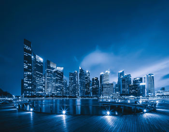 Illuminated buildings against blue sky at night