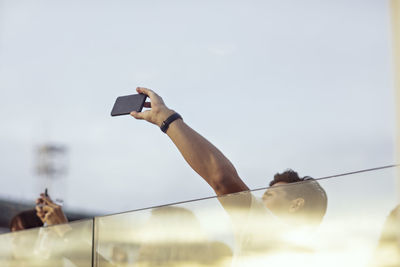 Man holding mobile phone against sky