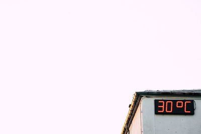 Low angle view of text on wall against clear sky