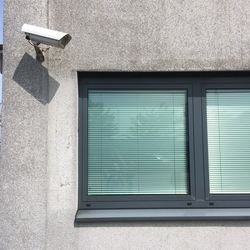 Security camera by closed window on wall of building