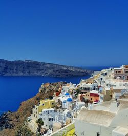 High angle view of townscape by sea against blue sky