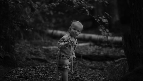 Portrait of girl standing on field at forest