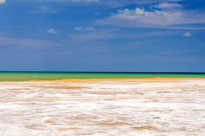 Salt flat by sea against blue sky