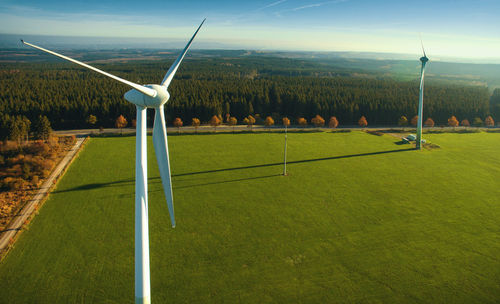 Wind turbines on field against sky