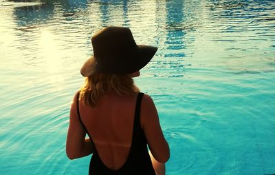 Rear view of woman in swimwear sitting in pool