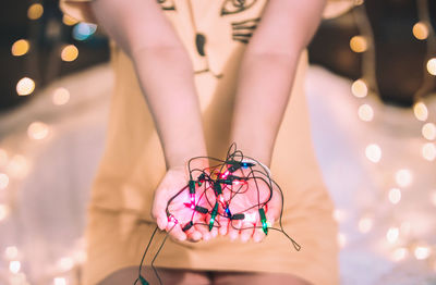 Midsection of woman with illuminated string lights