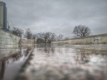 Reflection of bare trees in lake against sky