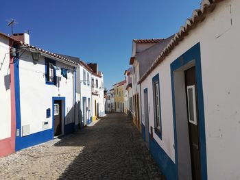 Street amidst buildings against clear blue sky